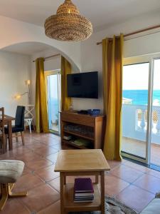 een woonkamer met een televisie en een tafel bij Casa Pedro in Salema - Oceanview & beach in Salema