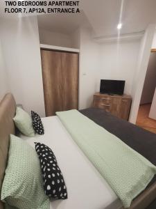 ブカレストにあるBlack and White Apartmentsのベッドルーム1室(黒と緑の枕が付いたベッド1台付)
