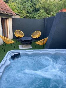 een hot tub met stoelen en een tafel in de achtertuin bij Au Bois d'Epenin - Gite et Spa in Beugin