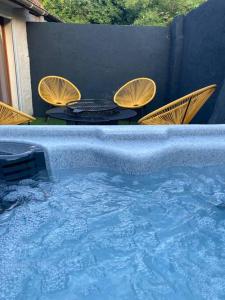 a large hot tub with chairs and a table in it at Au Bois d'Epenin - Gite et Spa in Beugin