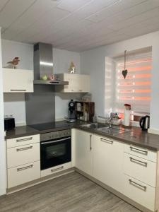 uma cozinha com armários brancos e um forno com placa de fogão em Ferienwohnung Petra em Rust