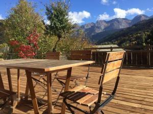 a wooden table and chairs on a deck with mountains at LE RUCHER DE LA VIGNETTE in Le Grand-Bornand +4 photos