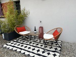 een patio met 2 stoelen en een tafel met een fles wijn bij Le studio d’Ambre in Chalon-sur-Saône