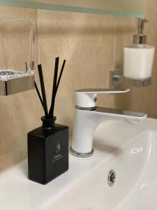 een wastafel in de badkamer met een toilet en een zwarte doos met sticks bij APARTMENT SAUNA INFRARED 2 in Szczecin