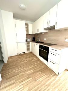 een keuken met witte kasten en een houten vloer bij FORSTHAUS 27 FREE GARAGE in Wenen
