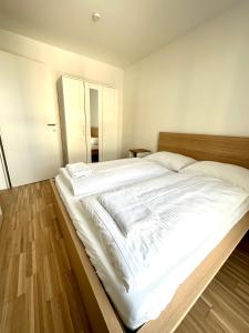 ein großes weißes Bett in einem Schlafzimmer mit Holzböden in der Unterkunft FORSTHAUS 27 FREE GARAGE in Wien