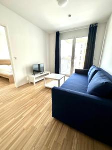 een woonkamer met een blauwe bank en een televisie bij FORSTHAUS 27 FREE GARAGE in Wenen
