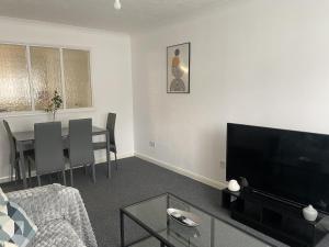 a living room with a couch and a table with a television at Spacious Apartment - Contractors and Family - LGW in Horley