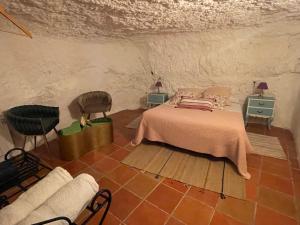 a bedroom with a bed and two chairs and a couch at Cueva de la Abuela María in Alcalá del Júcar