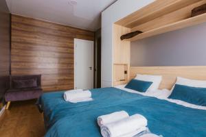 Un dormitorio con una gran cama azul con toallas. en Landscapes Hotel Kazbegi, en Kazbegi