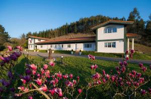a house with pink flowers in front of it at Apartamentos Turisticos Bizkar Bare in Sopuerta