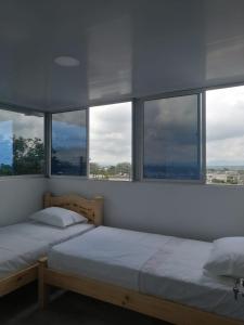 2 łóżka w pokoju z dużymi oknami w obiekcie Hotel viajeros w mieście El Mesón