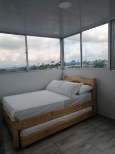 sypialnia z drewnianym łóżkiem i oknami w obiekcie Hotel viajeros w mieście El Mesón