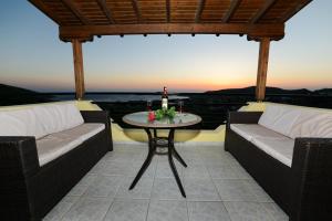 eine Terrasse mit 2 Stühlen und einem Tisch mit Aussicht in der Unterkunft Hotel Dina - Ξενοδοχείο Ντινα in Plati