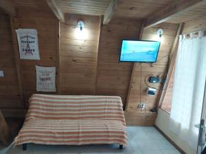 Habitación con TV en una pared de madera. en Cabaña alpina Las Lomas en Monte Hermoso