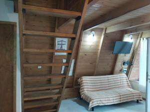 Habitación con paredes de madera y escalera con silla. en Cabaña alpina Las Lomas en Monte Hermoso
