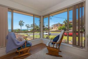 a living room with two chairs and a large window at Tranquil Surf Beach apartment. in Surf Beach