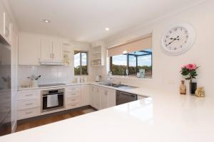 a white kitchen with a large clock on the wall at Tranquil Surf Beach apartment. in Surf Beach