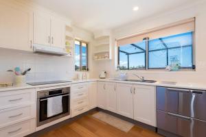 a kitchen with white cabinets and a window at Tranquil Surf Beach apartment. in Surf Beach
