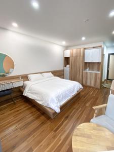 een slaapkamer met een wit bed en een houten vloer bij POTA Hotel & Apartment in Da Nang