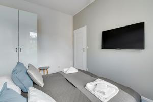 Un dormitorio con una cama con un televisor de pantalla plana en la pared. en Skandynawski - 4 osobowy apartament przy Monte Cassino by Grand Apartments, en Sopot