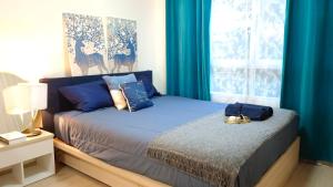 Schlafzimmer mit einem Bett und einem Fenster mit blauen Vorhängen in der Unterkunft Elio Del Ray in Bangkok