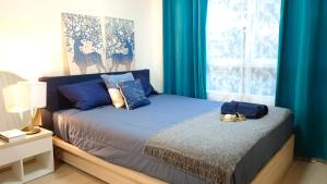 a bedroom with a bed and a window with blue curtains at Elio Del Ray in Bangkok +26 photos