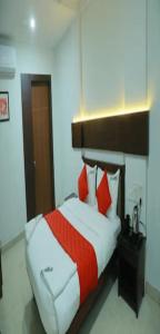 Schlafzimmer mit einem Bett mit roten und weißen Kissen in der Unterkunft Redbell Suites Manjeri in Manjeri