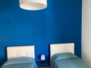 two beds in a room with a blue wall at H2Ome Il Cembalo in Genova