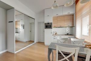 Una cocina con una mesa y algunos gabinetes blancos. en Skandynawski - 4 osobowy apartament przy Monte Cassino by Grand Apartments, en Sopot