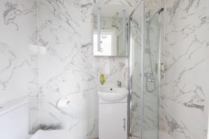 uma casa de banho branca com um chuveiro e um lavatório. em The Anson Hotel - Conveniently Located Sweet Space Near Transportation Stations em Londres