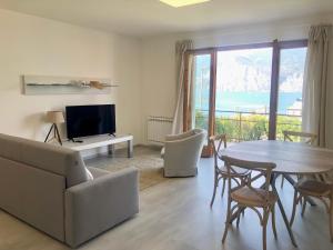 uma sala de estar com uma mesa e cadeiras e uma televisão em Panoramic Apartment em Malcesine