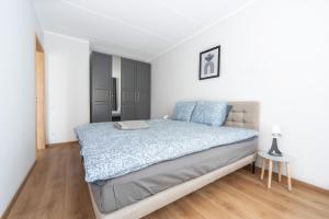 1 dormitorio con 1 cama grande en una habitación blanca en Cozy&Chic - A modern apartment with a garden terrace, en Riga