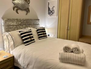 a bedroom with a white bed with two towels on it at Driftwood Lodge in Salcombe