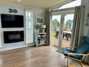 a living room with a fireplace and a tv at Driftwood Lodge in Salcombe