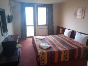 a hotel room with a bed and a desk and window at Family hotel Elena in Arbanasi