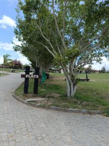 a park with a sign that says plays next to a tree at Flat Monte Castelo Gravatá in Gravatá