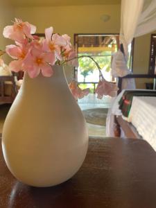 eine weiße Vase mit rosa Blumen auf dem Tisch in der Unterkunft Kileleni in Kilindoni
