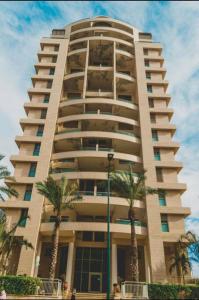 a tall building with palm trees in front of it at proche kikar , piscine, spacieux et agréable in Netanya