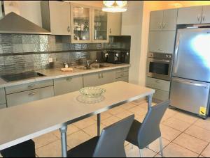 a kitchen with a table and a stainless steel refrigerator at proche kikar , piscine, spacieux et agréable in Netanya