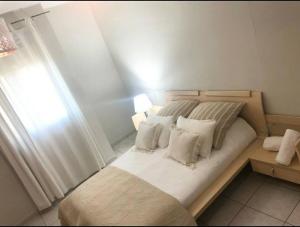 a small bedroom with a bed with white pillows at proche kikar , piscine, spacieux et agréable in Netanya