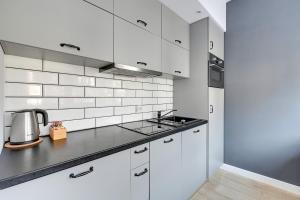 a white kitchen with white cabinets and a sink at Loft Apartment Haffnera Sopot by Grand Apartments in Sopot