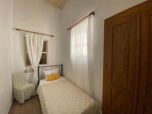 a bedroom with a bed and a chair and a window at Marthas Traditional House in Symi