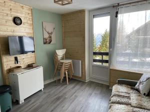 salon z telewizorem i stołem z krzesłem w obiekcie RISOUL 1850 - Appart' 4 personnes ski aux pieds w mieście Risoul