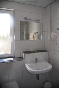 a white bathroom with a sink and a window at Hotel am Bad in Tübingen