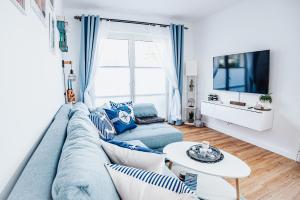 ein Wohnzimmer mit einem blauen Sofa und einem Tisch in der Unterkunft Ferienwohnung Sunset bei Warnemünde in Rostock