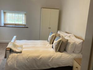 Un dormitorio con una cama blanca con almohadas. en 2 Malt Kiln Cottages en Grizebeck