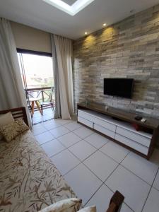 a living room with a tv on a brick wall at Flat Monte Castelo Gravatá in Gravatá
