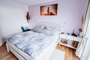 een witte slaapkamer met een bed en een foto aan de muur bij Ferienwohnung Sunset bei Warnemünde in Rostock
