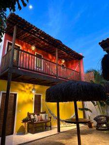 a house with a balcony and a hammock in front of it at Alto Mar Flats in São Miguel do Gostoso